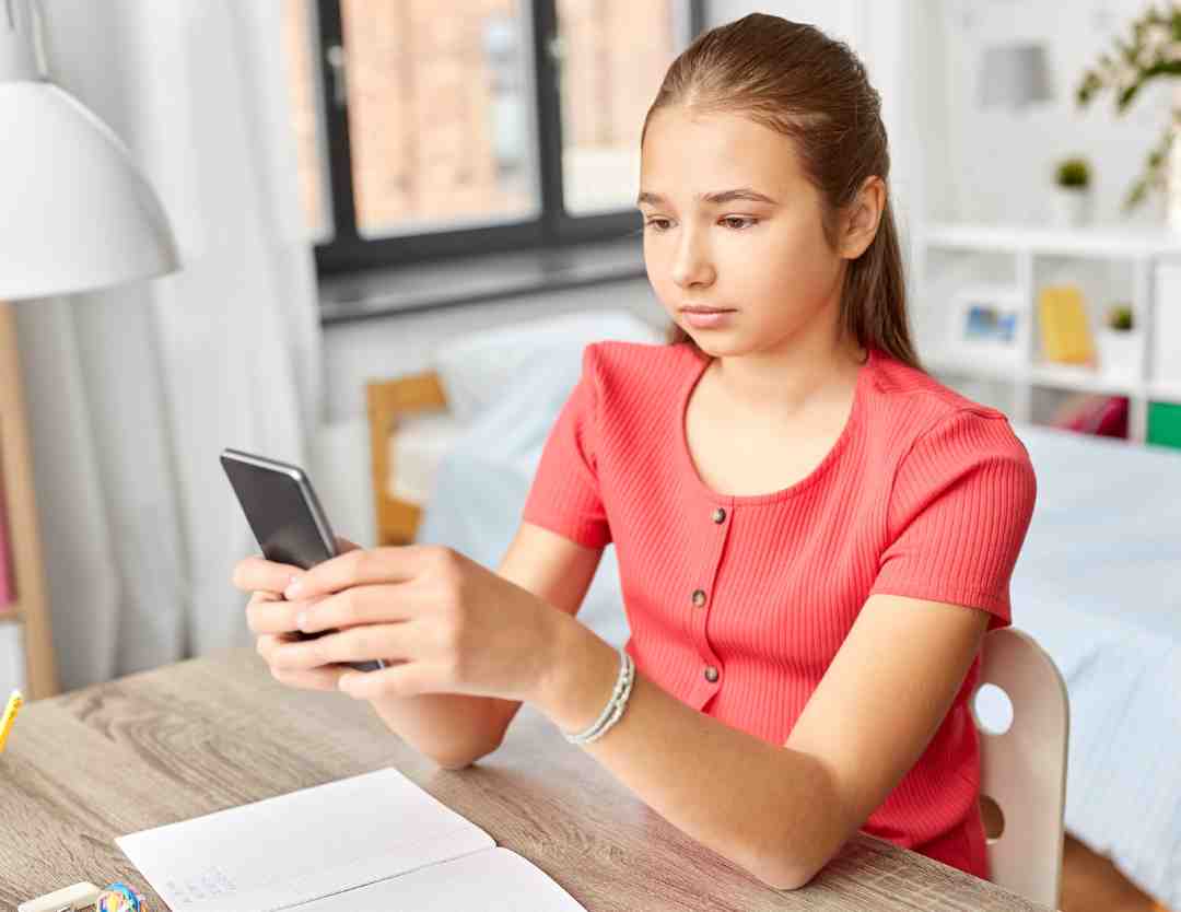 Young girl using a smartphone in an inclusive learning environment, representing Evolved Education Company's focus on neurodiversity inclusion in private schools.